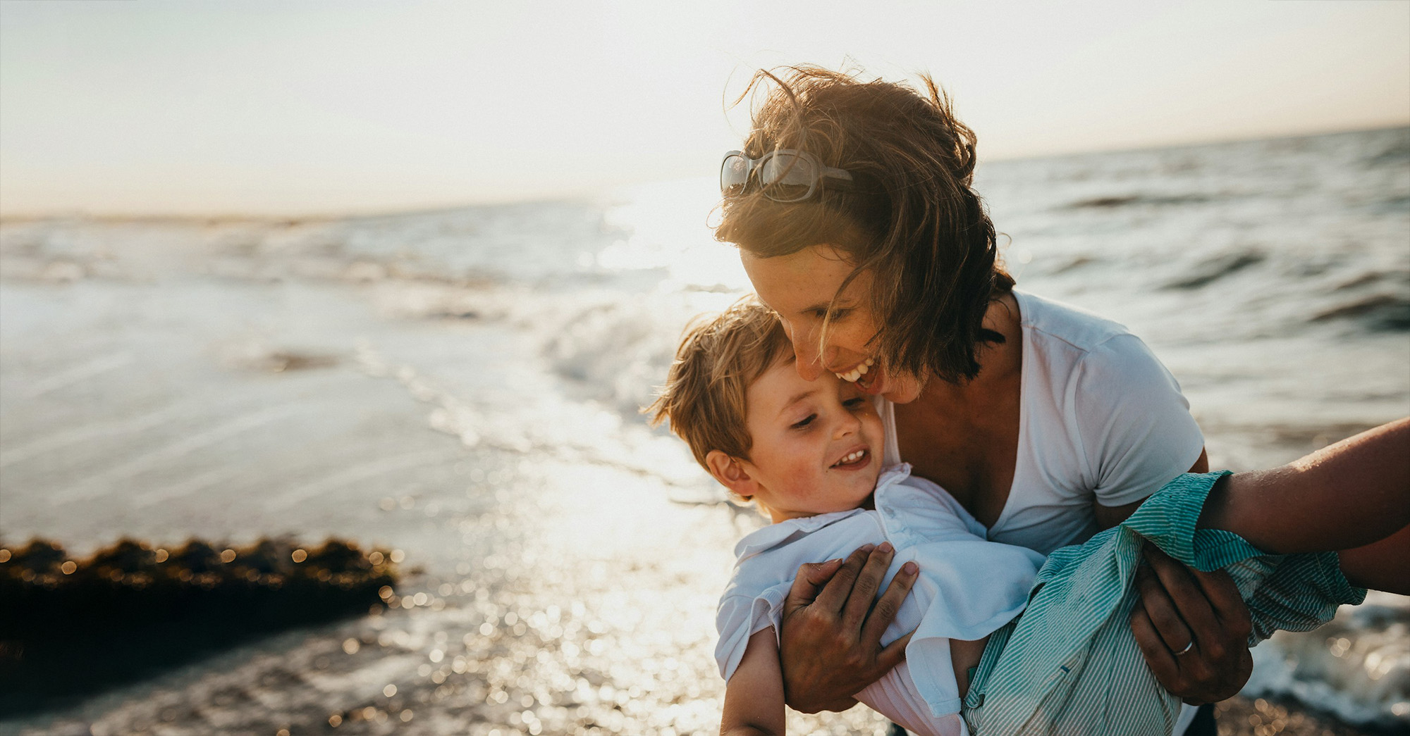 A mother embracing her son at the beach, golden hour